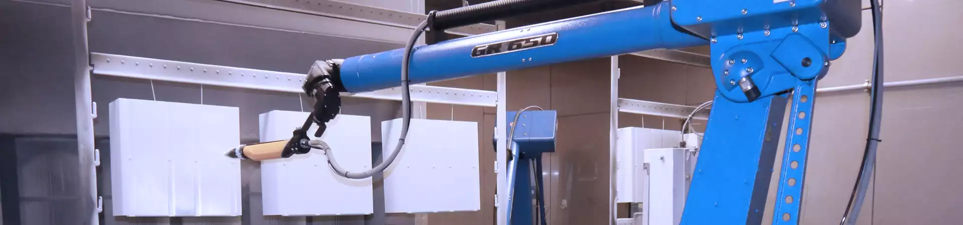 Headerbild: Oberflaechenveredelung, Roboter in Kabine pulvert Blechteile weiss