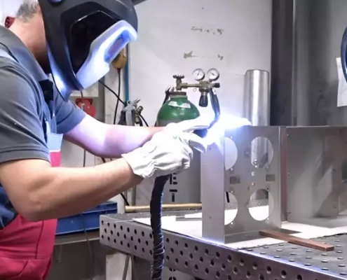 Headerbild für Webseite Prozesse Schweißen: Mitarbeiter schweißt Elemente für eine Baugruppe von Hand.